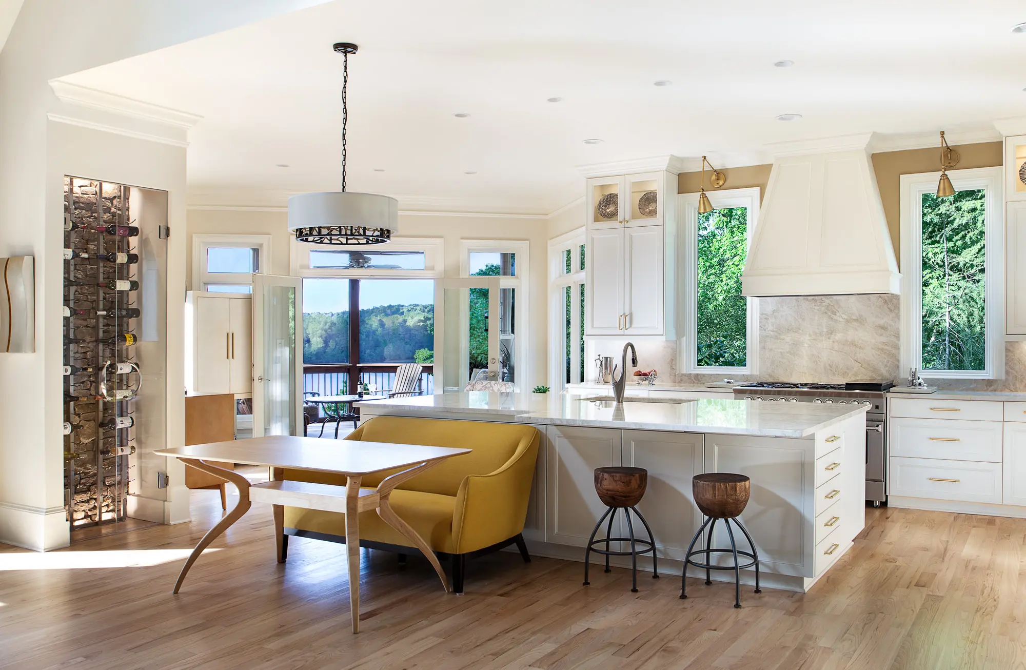 Spacious kitchen with a wine rack, mustard dining nook, and a scenic view through large windows.