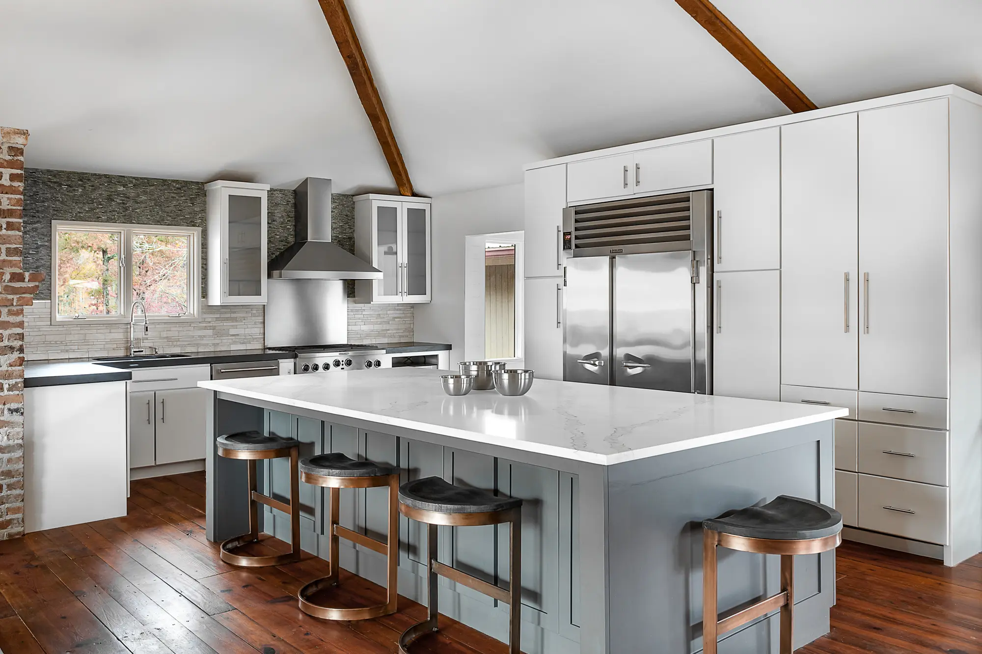 Spacious kitchen with white cabinetry, exposed beams, and large island by Michael James Remodeling.